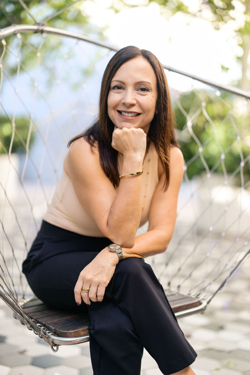 Mom sitting in a rocking chair in the nursery and holding her newborn baby who is looking up with his blue eyes in Brickell, FL.