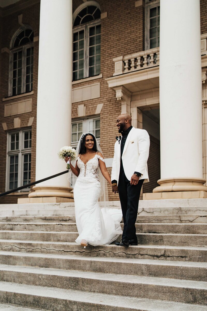 Bride and groom holding hands and walking down a staircase at a historical building in Georgia