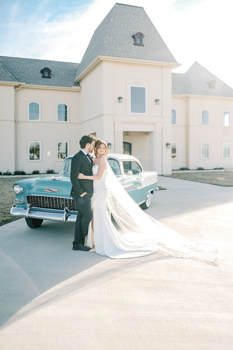 Fort Worth Wedding Photographer | DFW Photographer Rae De Lain Weddings Light and Airy | Bride and groom embraces in front of vintage car at Chateau Joli