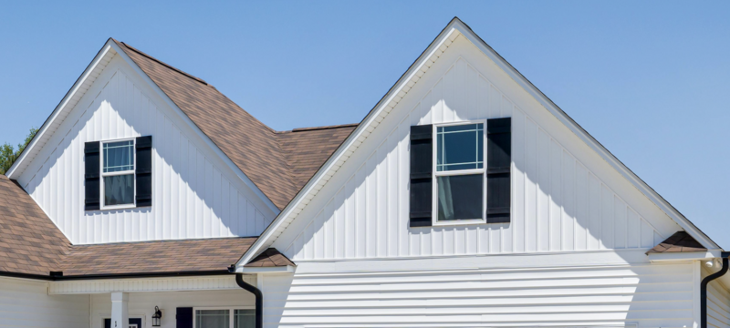 A close up of a white modern house with white board and batten vinyl siding installed by Perry Vinyl Windows & Doors in Hazard, KY and black shutters