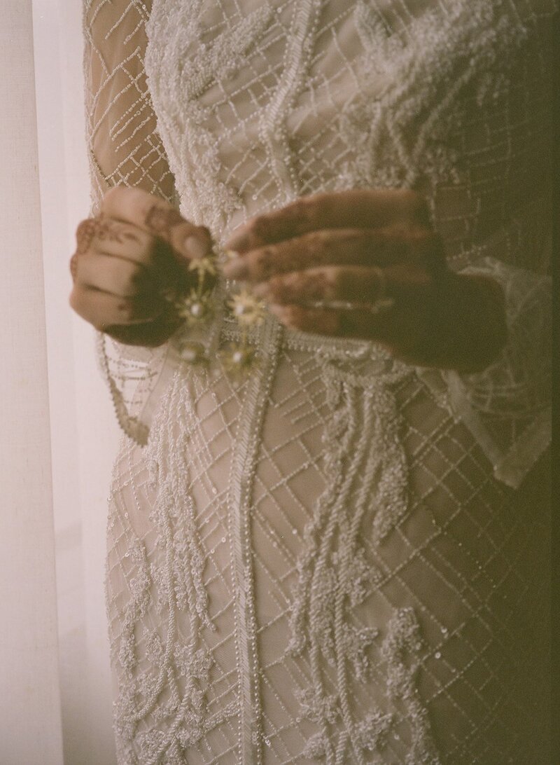 Bride holding a pair of earring with her hands that have henna design
