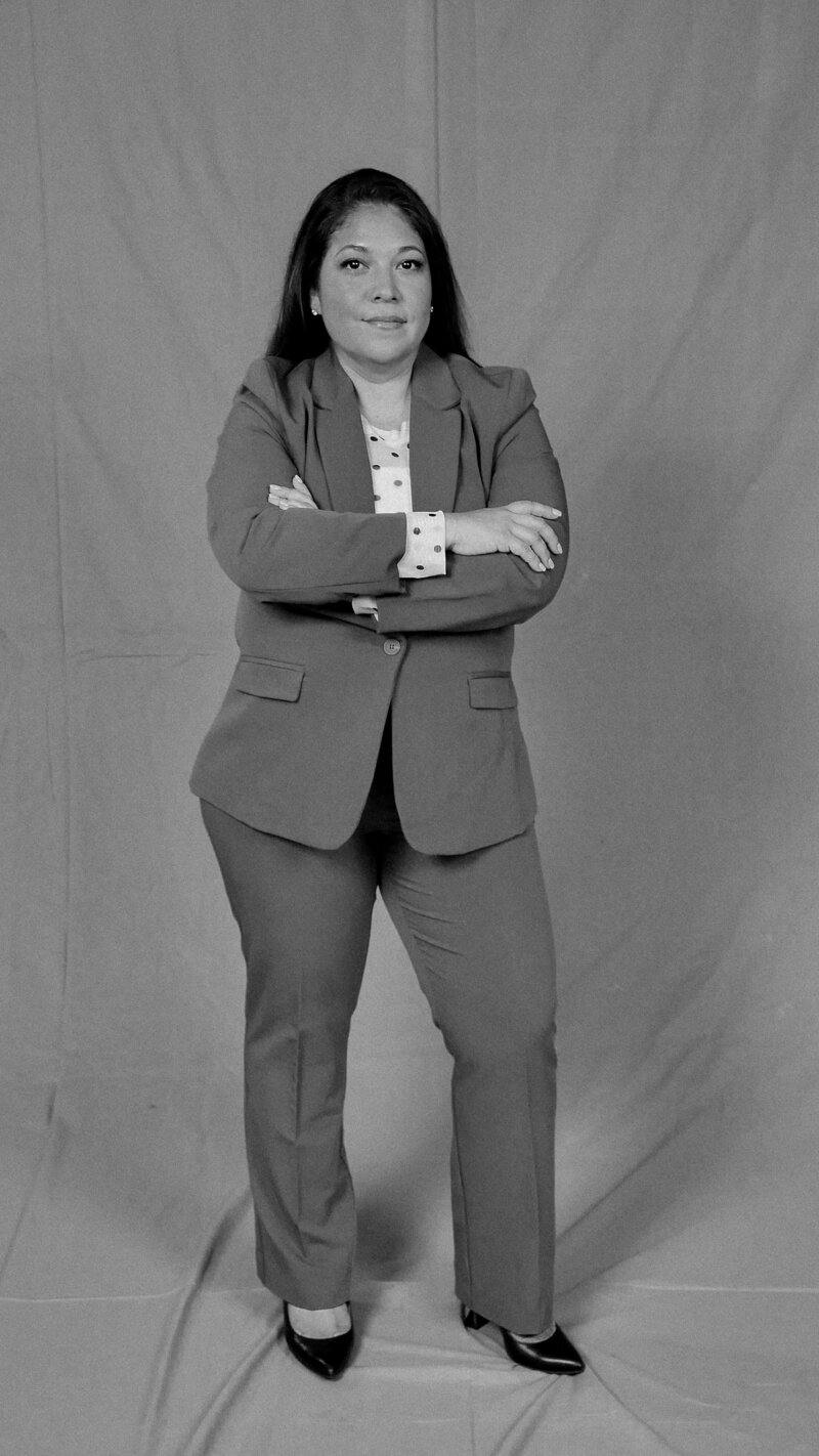 Teresa stands while crossing her arms in this black and white photo.