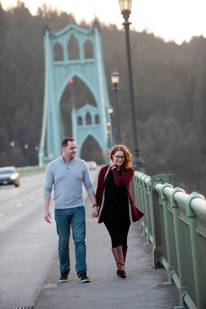 a couple walk over the st johns bridge during their engagement session