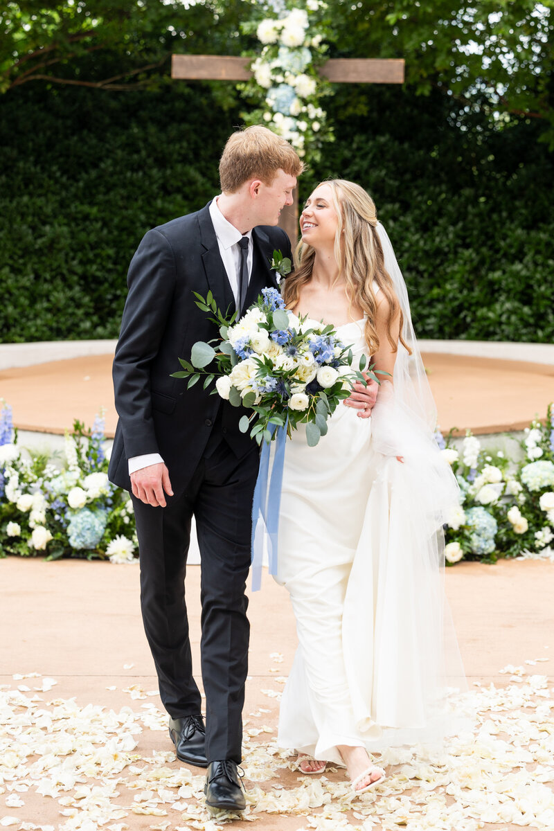 Spring wedding at WinMock at Kinderton, designed by Charming Carolina — bride and groom walking hand in hand down the petal-lined aisle after their ceremony.