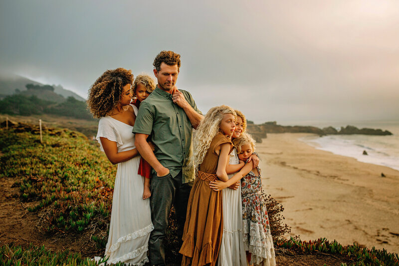 family facing the ocean at the beach