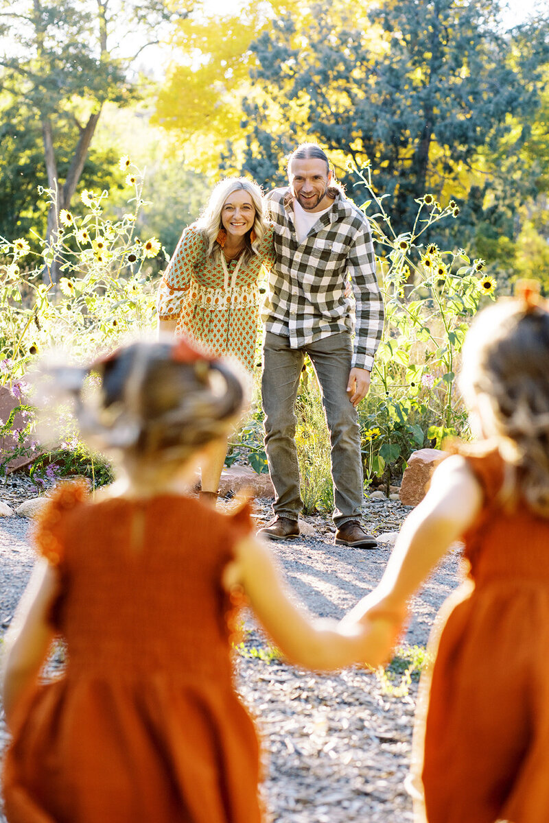 parents and two young kids stand in front of mountains of boulder, colorado for a family photo