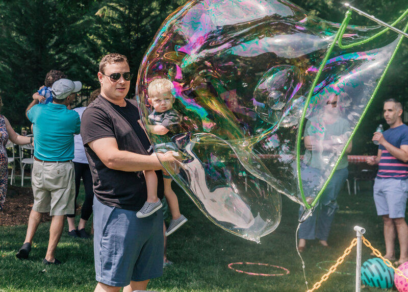 Father and son admire a giant bubble at a casual party