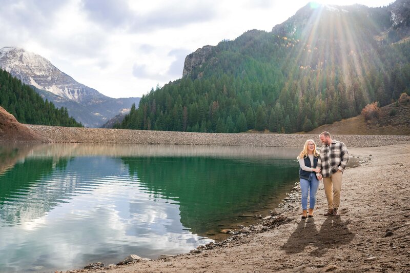 Couple walking along the water in Utah surrounded by mountains and Mount Timpanogos