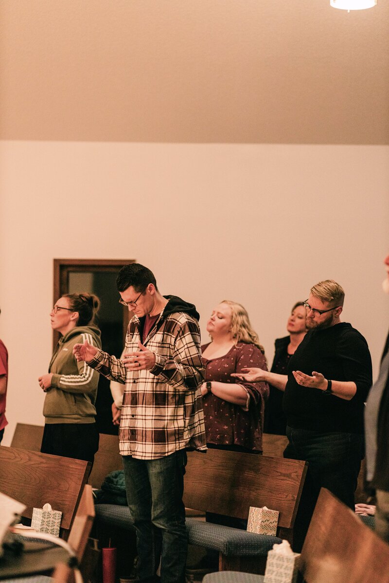 A group of people worshipping together with their eyes closed and hands out