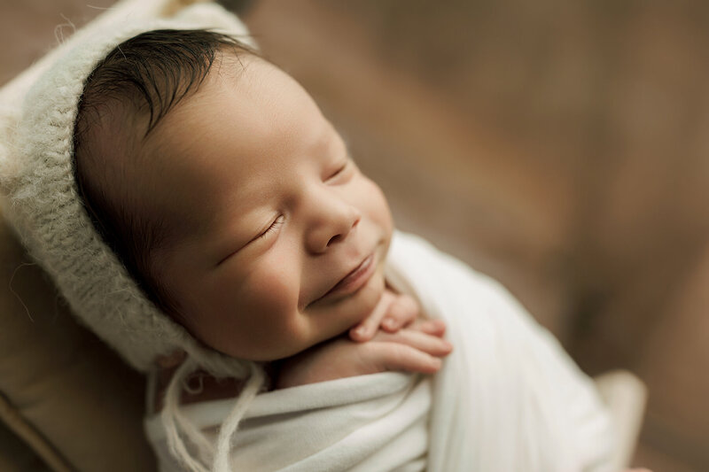 Adorable baby boy wrapped up in cream blanket
