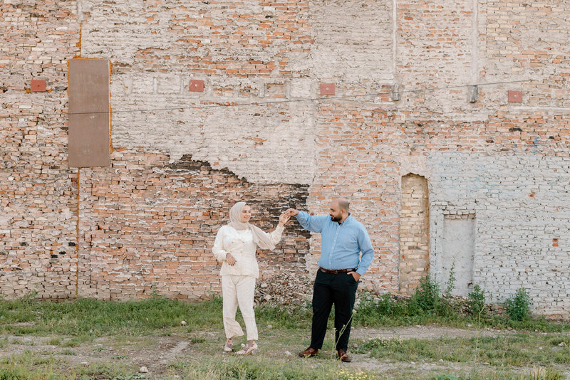 bride and groom dance in front of brick wall downtown brantford