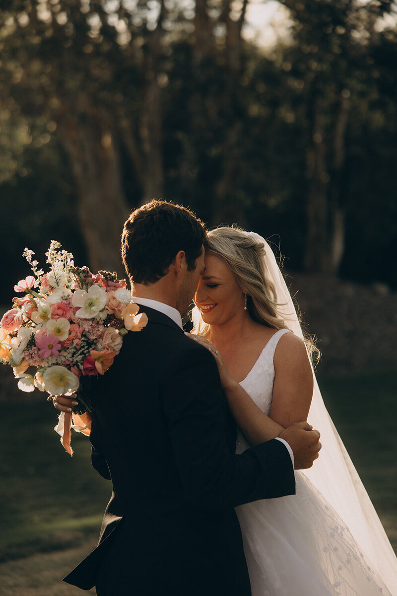 Bride holding a bouquet and smiling at the Groom during an outdoor first look, photographed by a wedding photographer Sunshine Coast.