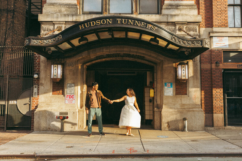 couple in love standing outside of hudson tunnel in nyc holding hands during sunset