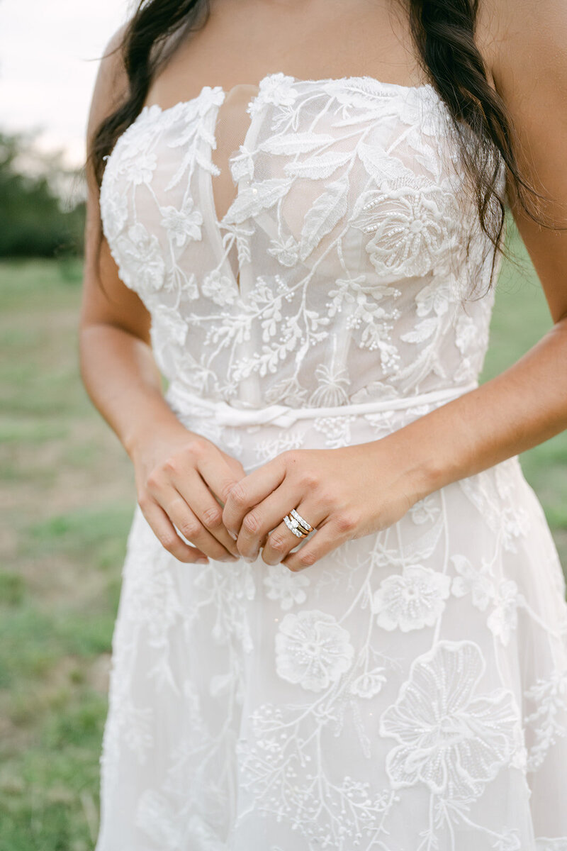 Close-up of bride’s hands and floral lace gown during wedding at Stoney Creek Wedding Venue in San Antonio, Texas.