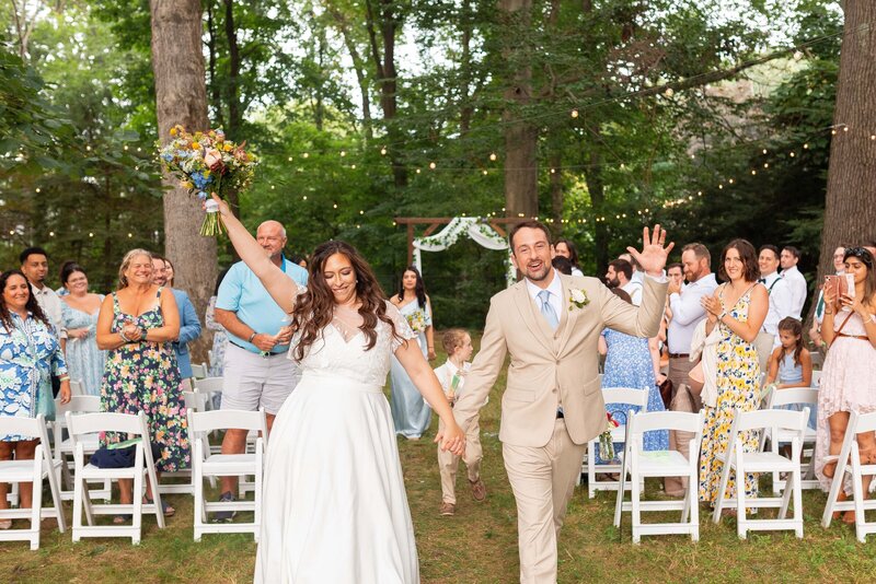 Bride and groom cheer as they walk down the aisle after their wedding ceremony.