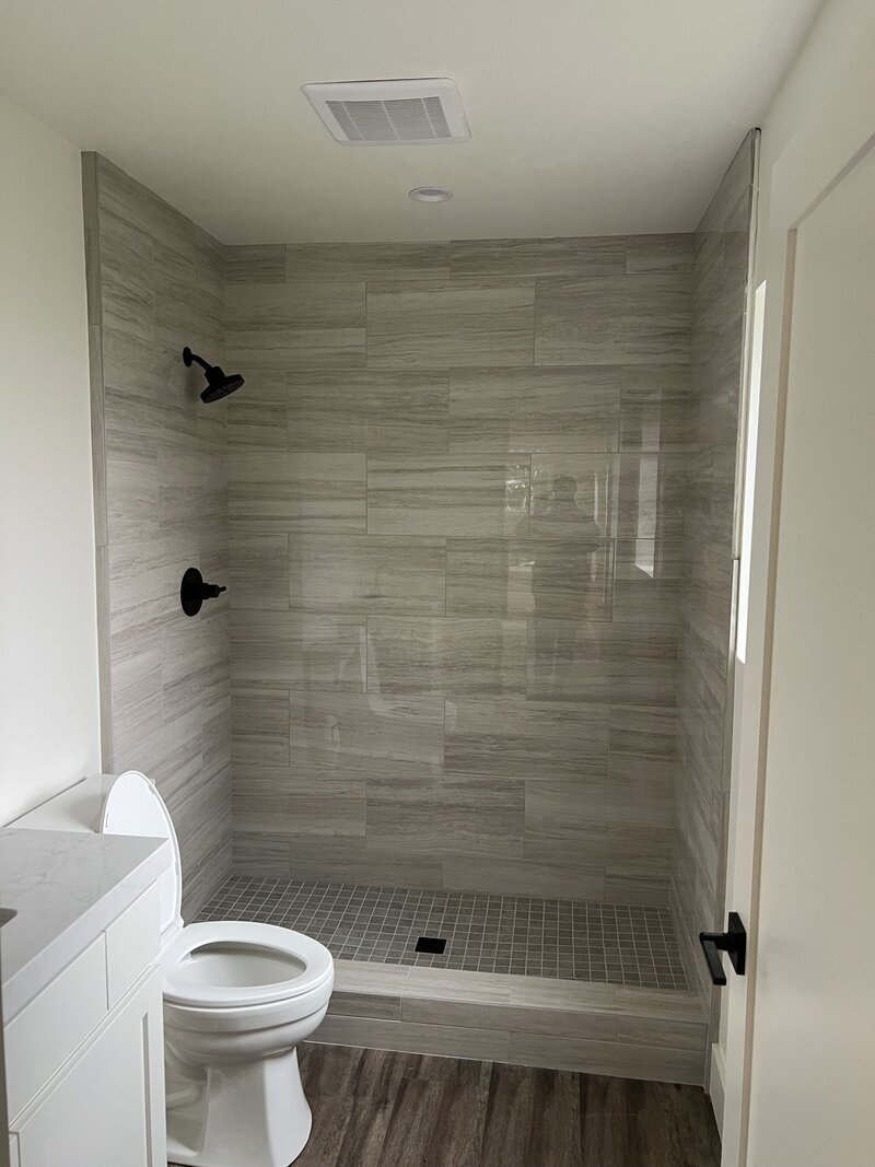 A new shower with large tiles and black hardware, remodeled in the Inland Empire