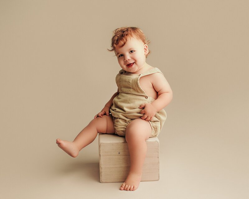 One-year-old with soft, sweet smile in bright studio setting