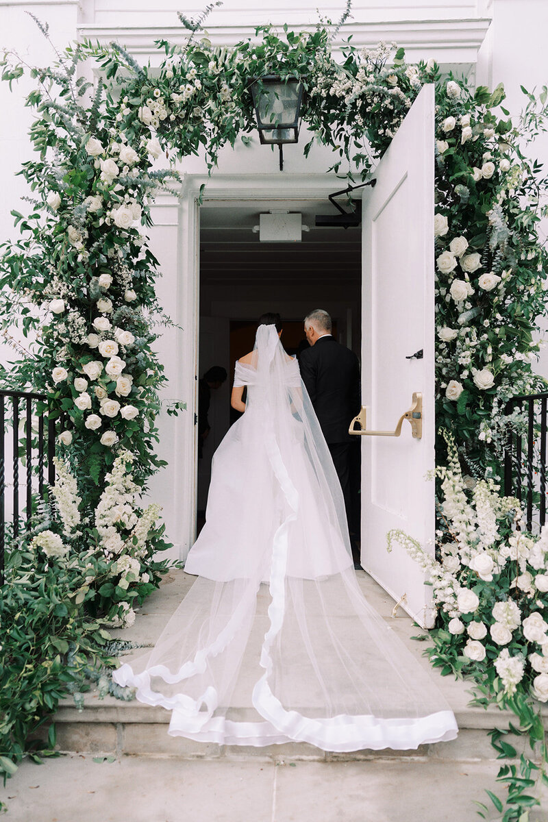 Luxurious green and white garden  flowers in arch framing door into wedding. 