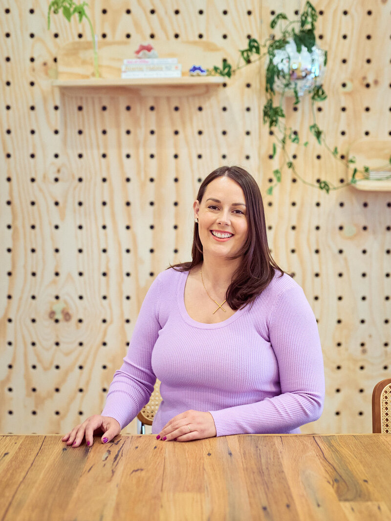 Claire Dicarlo sitting smiling at a desk.
