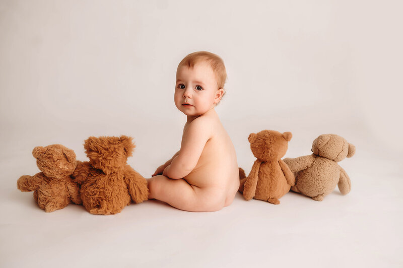 Baby peers at the camera during Milestone, Cake Smash Photoshoot in Asheville, NC.