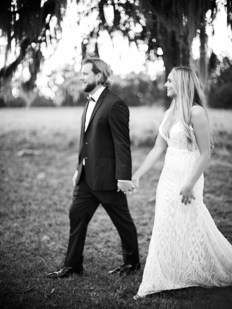 bride and groom hold hands walking into reception tent