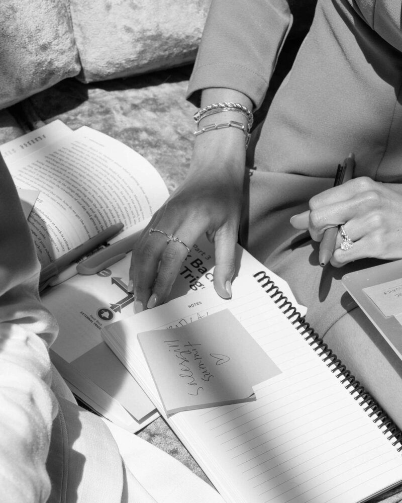 black and white photo of women looking through books