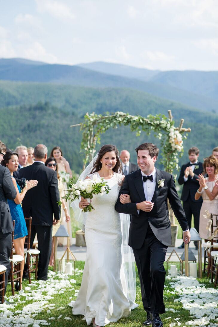 Testimonial photo, bride and groom walk down the aisle while guests celebrate