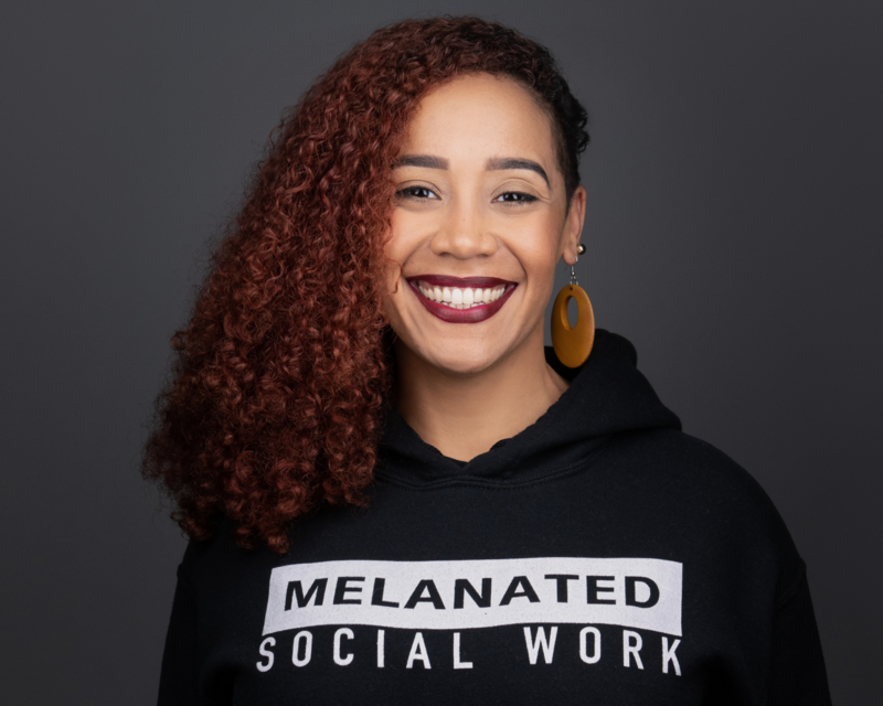 Photo of Vanessa Sujey smiling and wearing a short that says Melanated Social Work