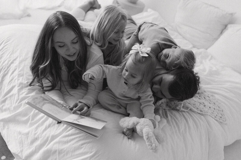 The family is cuddled up together and reading a book together in their home