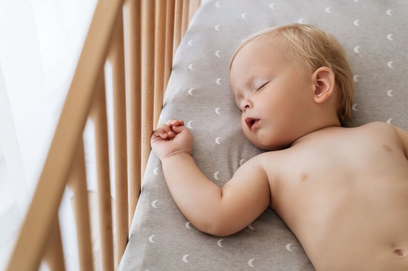 baby sleeping on their back in a crib