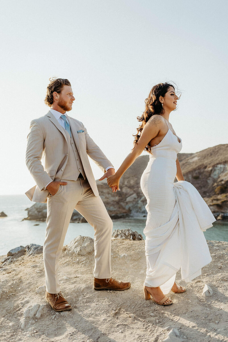 couple standing on cliff overlooking catalina island wearing wedding attire