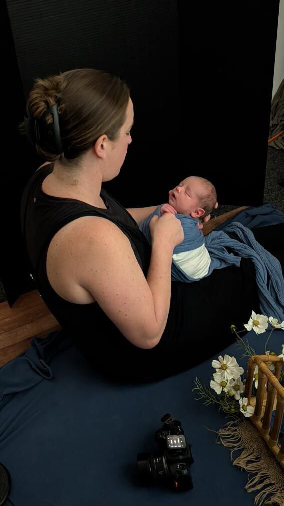 Grand Rapids newborn photographer tenderly wrapping a newborn in a blue wrap preparing them for the photograph