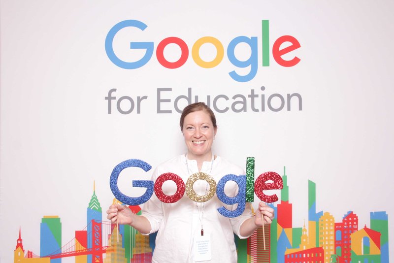 woman holding a google prop front of a good for education backdrop