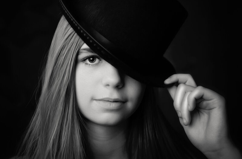 tween-girl-holding-black-hat-over-one-eye-in-arlington-tx-studio-in-black-and-white