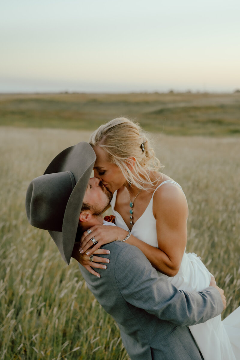 bride and groom kissing in a field at their wedding in dallas