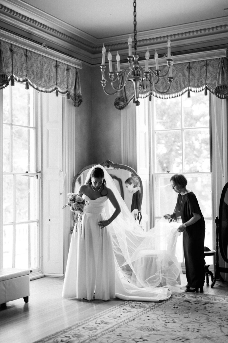 Mother of bride fluffs bride's veil in Glen Foerd bridal suite during wedding