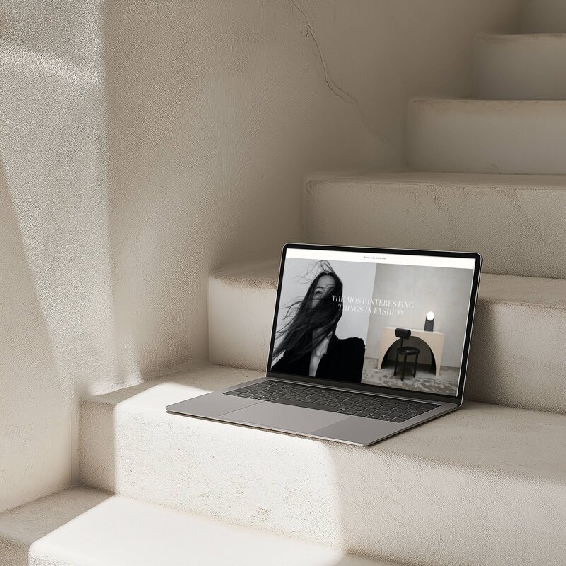 Shopify store homepage on an open Macbook Pro laptop set on top staircase 