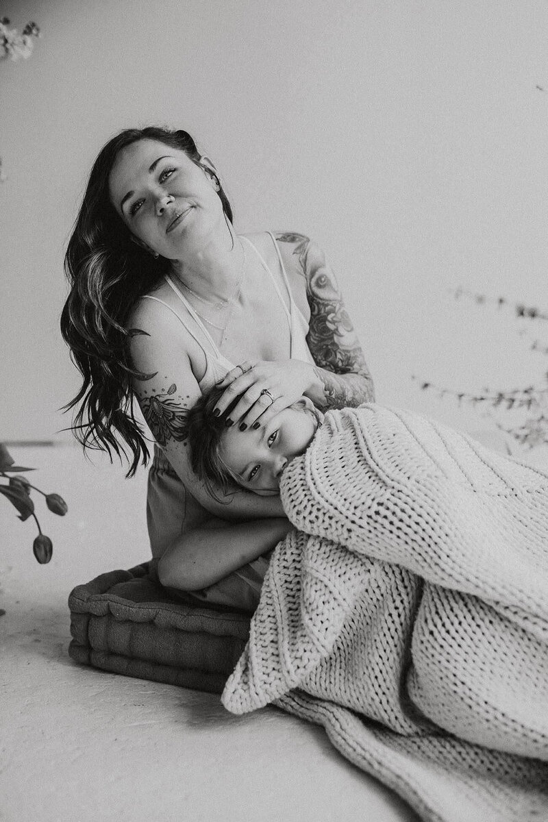 a daughter kissing her moms cheek as shes holding wildflowers standing in a field