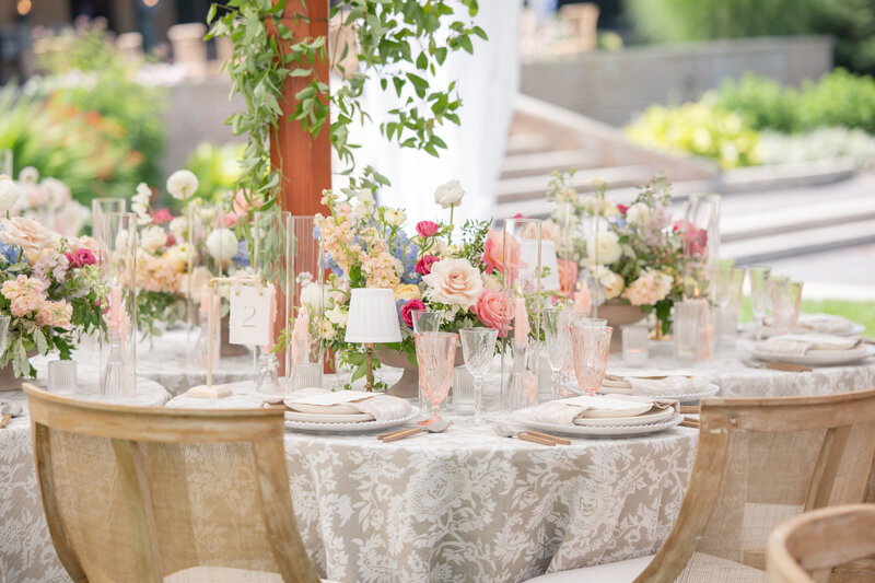 Lush wedding reception dinner table with abundant florals under a white tent at a private estate celebration
