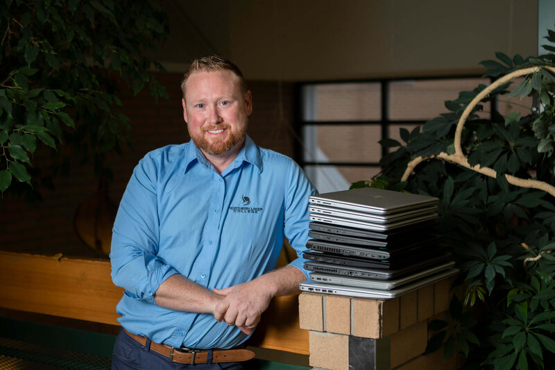 computer technician stands by a stack of laptops