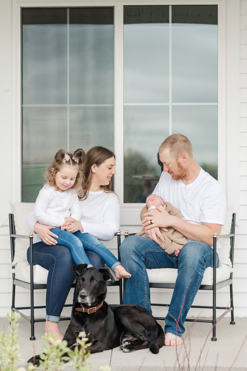parents sitting with their newborn, toddler, and dog
