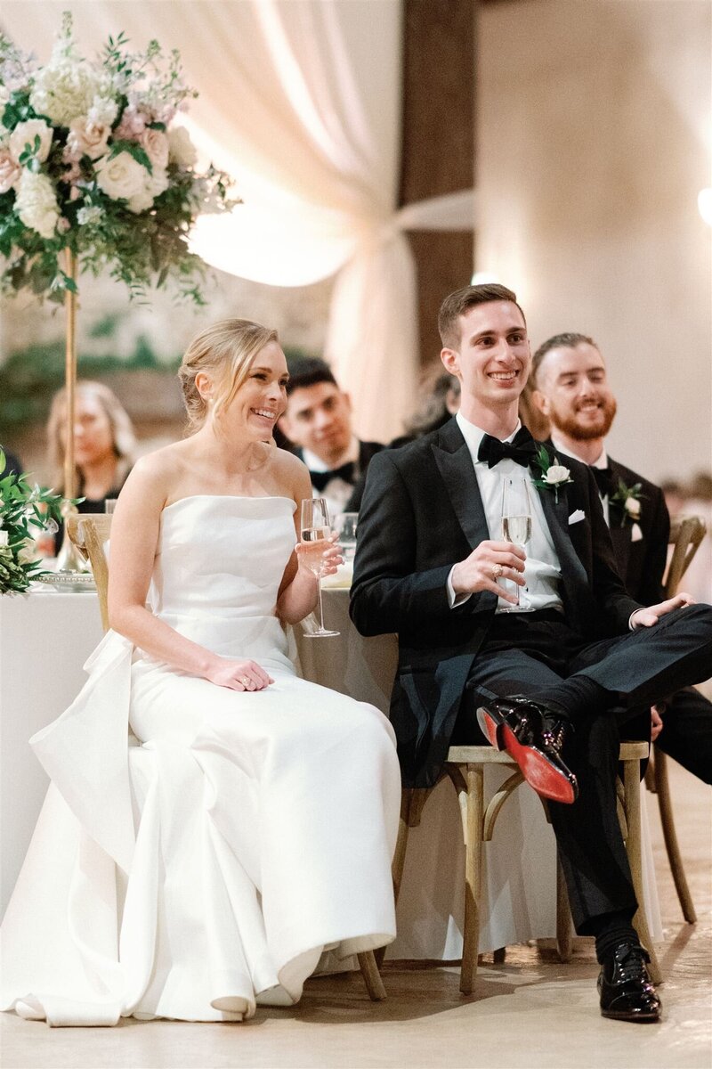 bride and groom watching toasts at wedding reception