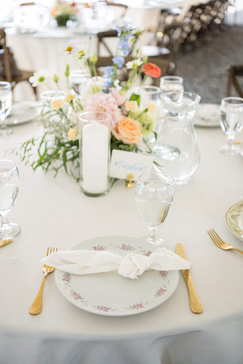 Wedding details with china, candles, flowers and place settings at a reception planned by Birdie June Events and Rentals. 