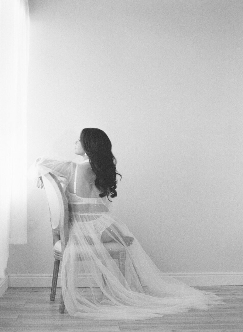 A woman poses for vintage boudoir photos on black and white film in Denver.