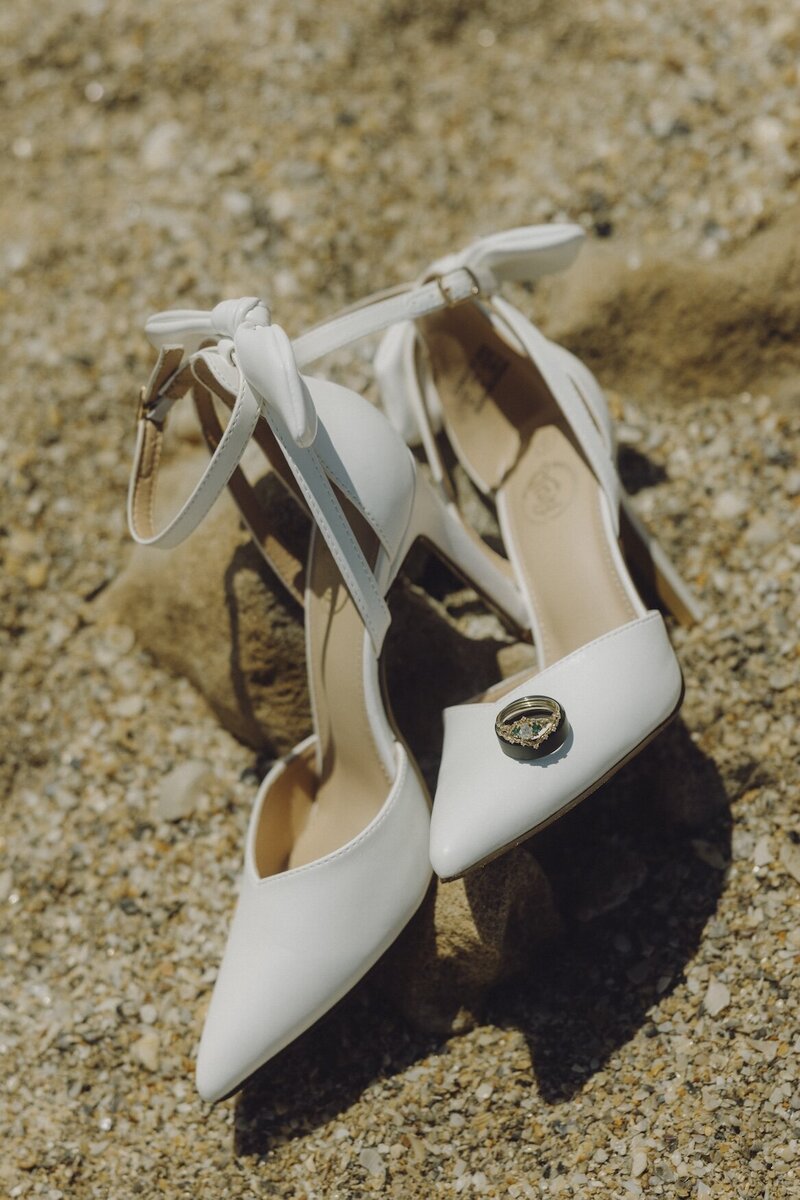 brides shoes and rings on the beach