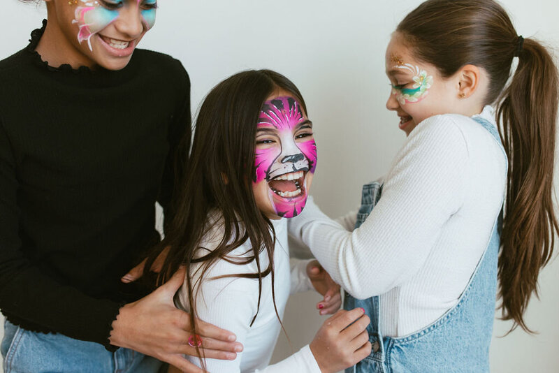 three girls laughing together with painted faces