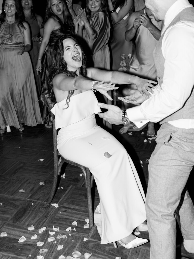  wedding reception party as the bride laughs in the groom dances with her during the wedding reception at their California luxury wedding