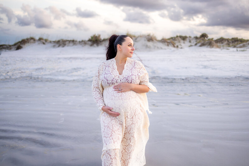 Expecting young mother posing on beach in white sand