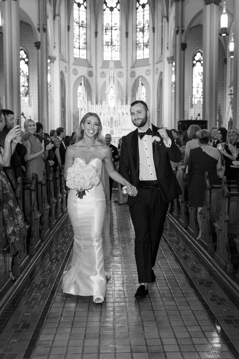 A candid photo of a happy couple walking down the aisle after their ceremony at St. Francis DeSales in Cincinnati.