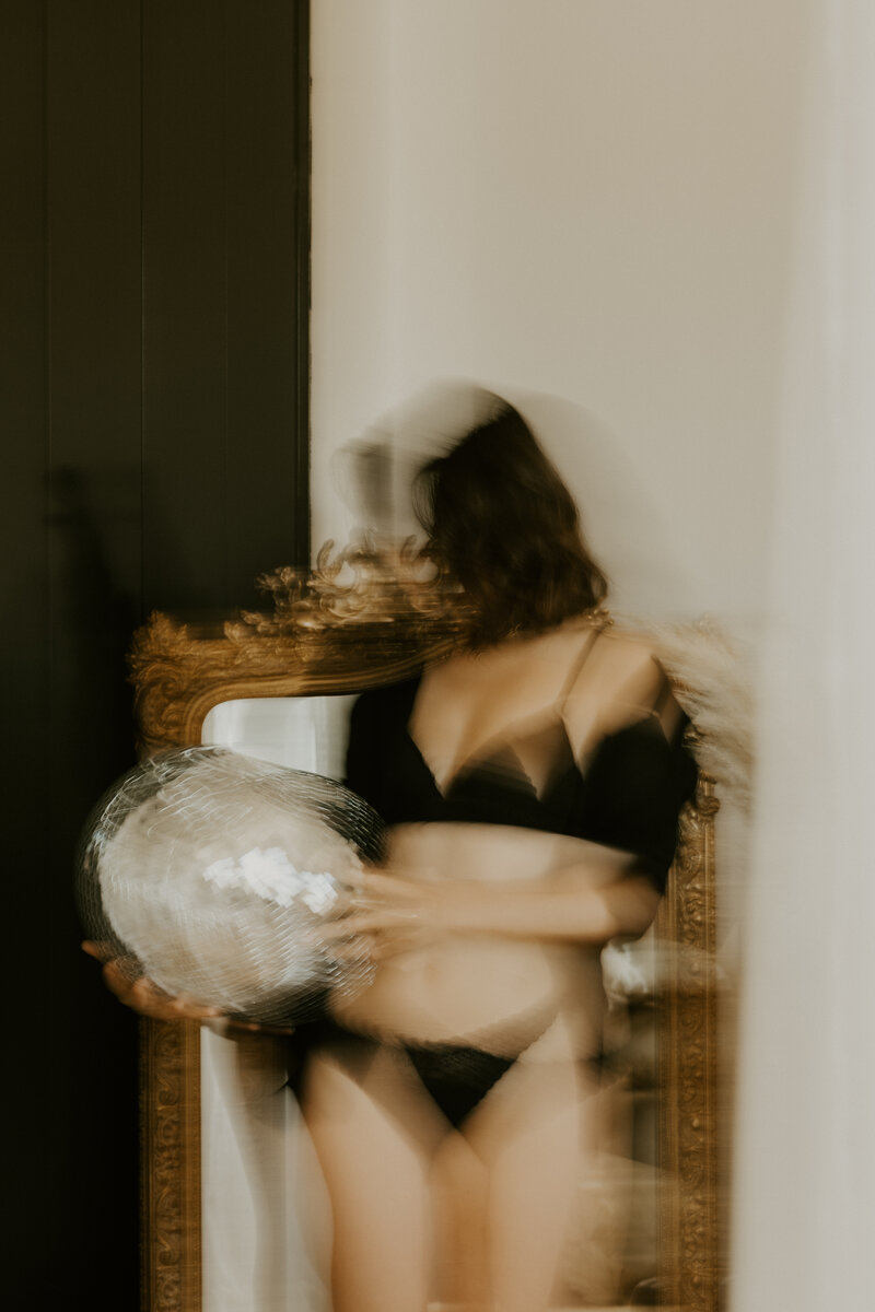 Séance photo portrait capturant une femme assise par terre, adossée à un mur, yeux fermés. Visage baigné de lumière naturelle.